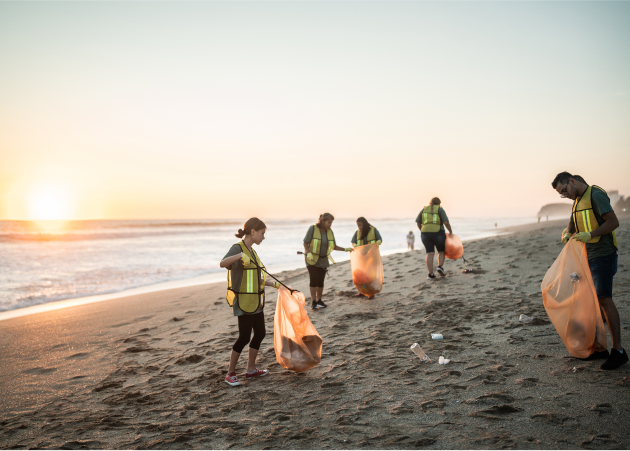 Five individuals on a beach picking up garbage