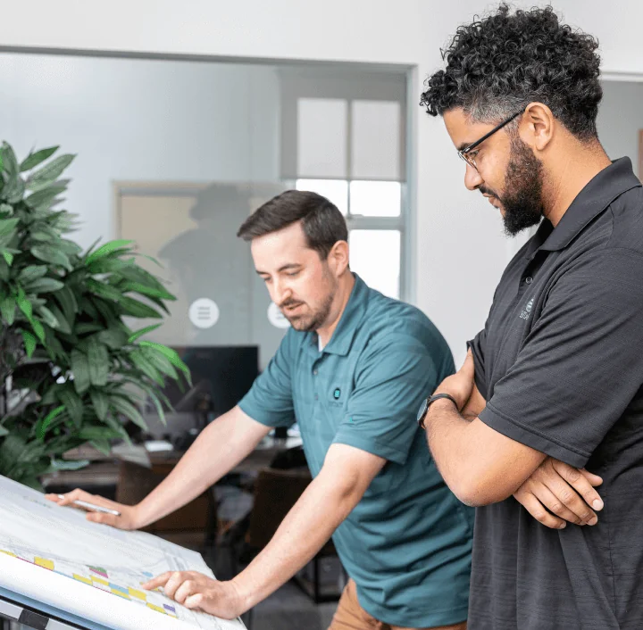 Two individuals in an office looking at project site plans