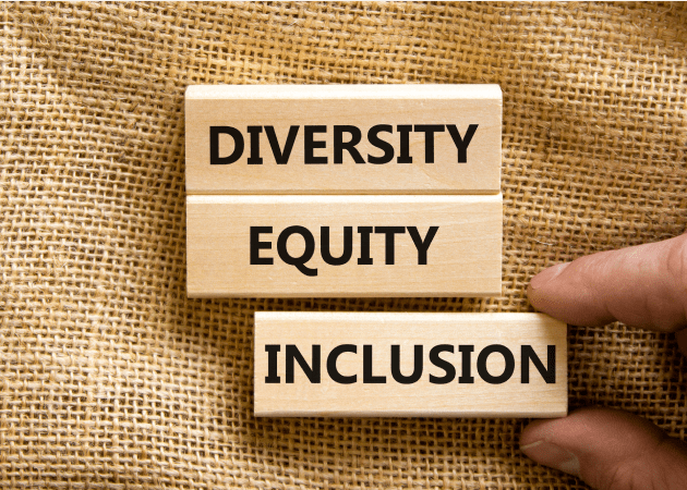 DEI words on a burlap backdrop.jpg Three small wooden blocks with the words “Diversity,” “Equity” and “Inclusion”