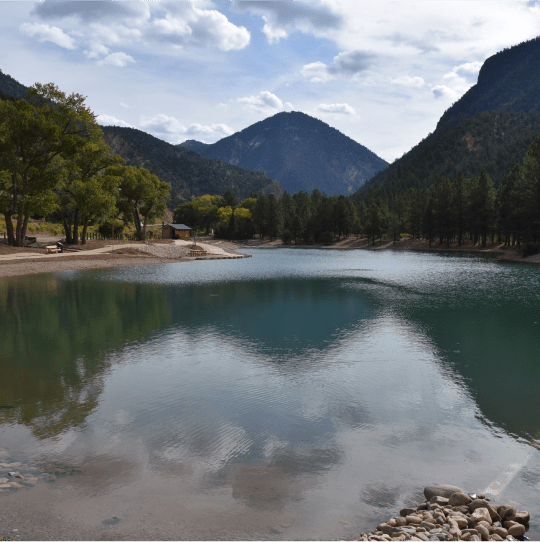 A calm lake surrounded by trees and mountains