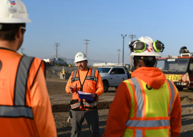 Site manager in safety gear leading safety meeting on project site