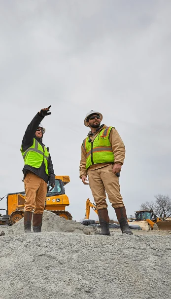 Two workers in safety gear standing on a project site having a discussion