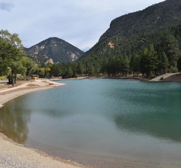 A calm lake surrounded by trees and mountains