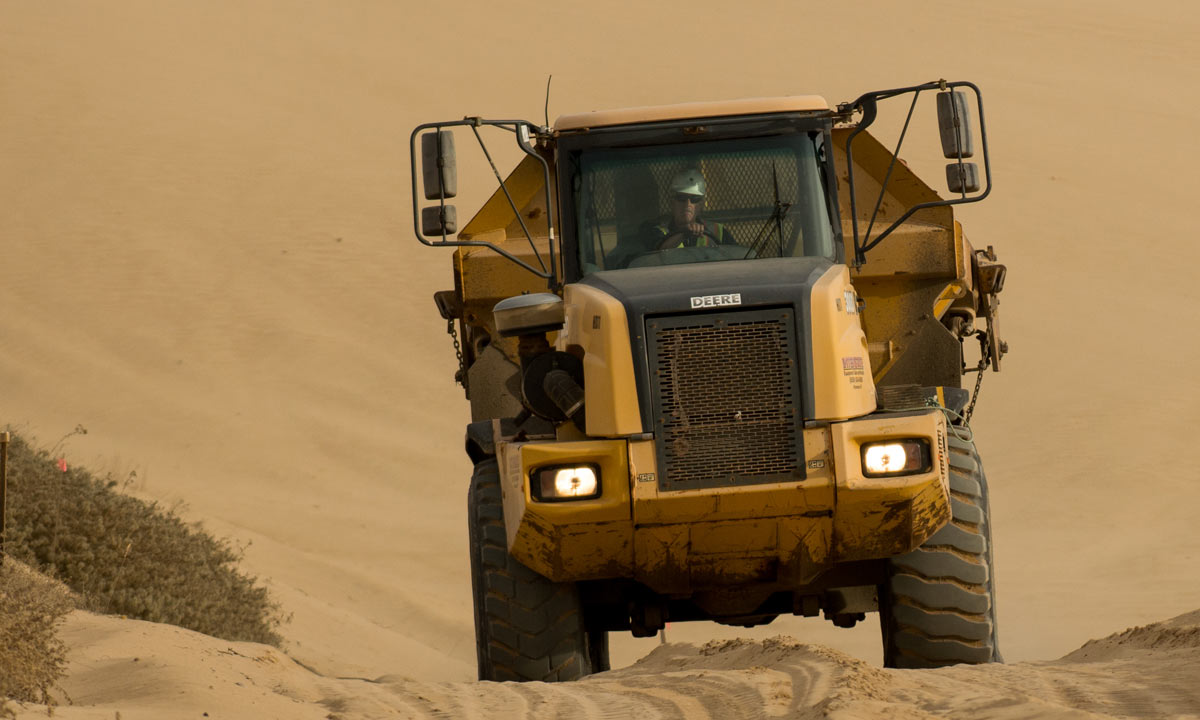 flatbed truck driving over a mound of dirt